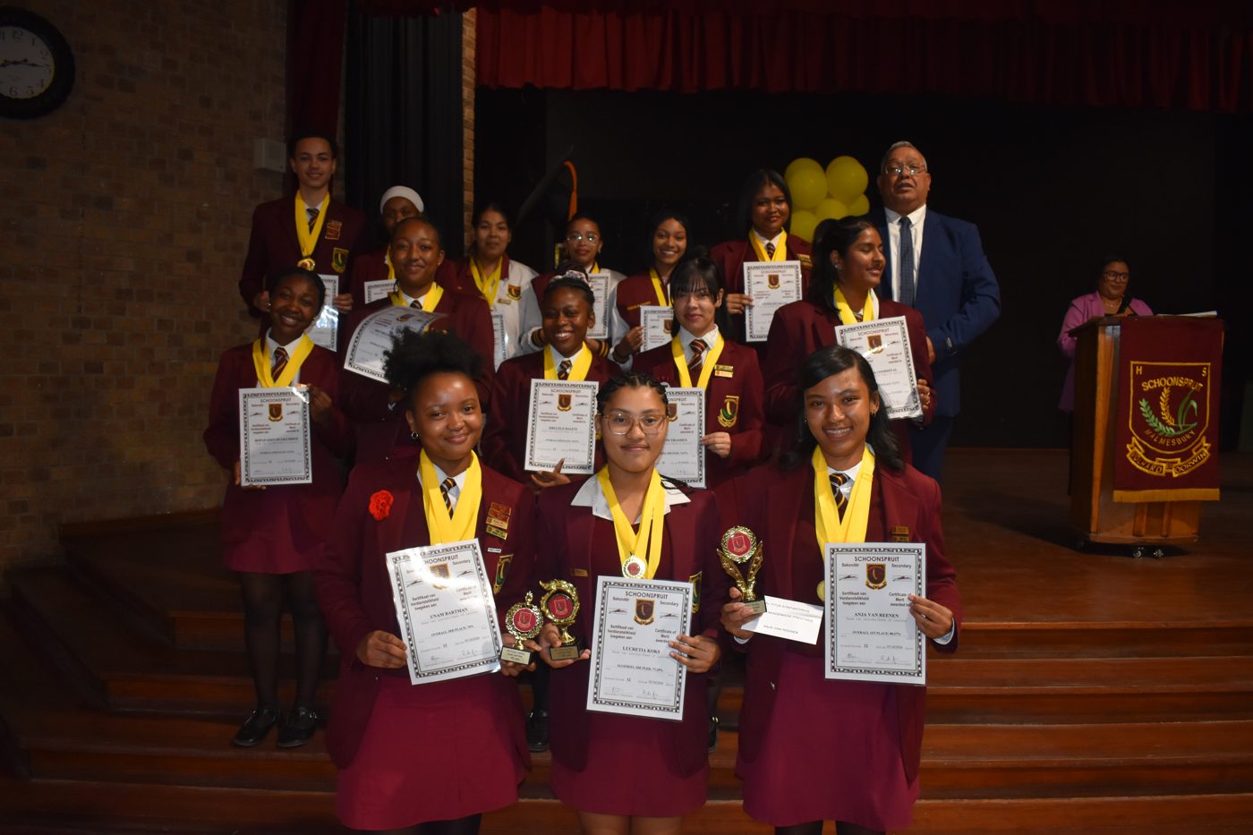 Learners posing with awards on stage at prize-giving